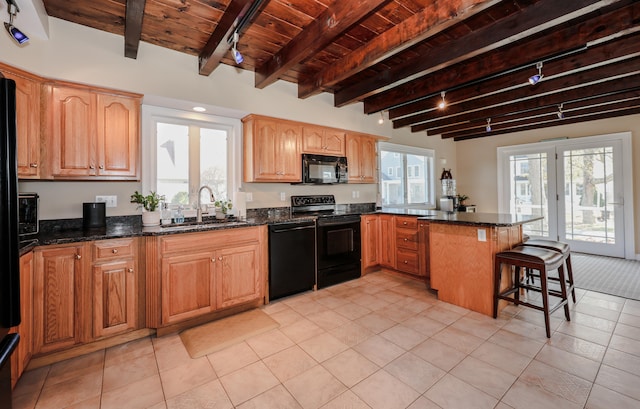 kitchen featuring dark stone countertops, black appliances, kitchen peninsula, and a kitchen breakfast bar