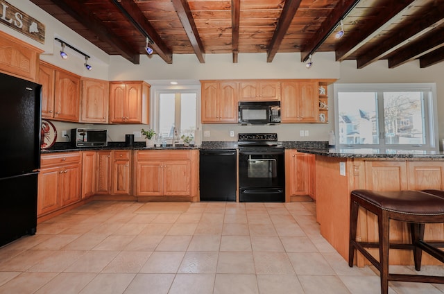 kitchen featuring beamed ceiling, dark stone countertops, black appliances, light tile patterned flooring, and sink