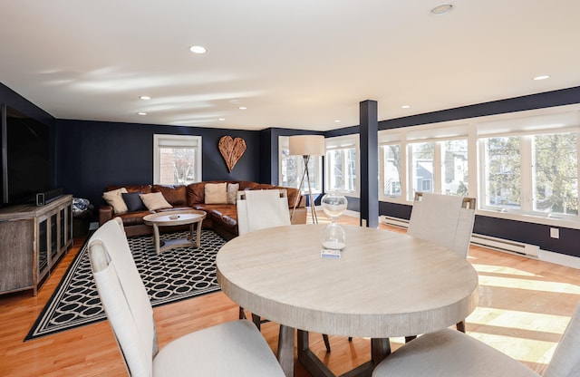 dining space with baseboard heating and light hardwood / wood-style floors