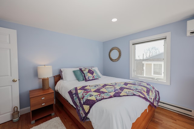 bedroom featuring a baseboard heating unit and hardwood / wood-style floors