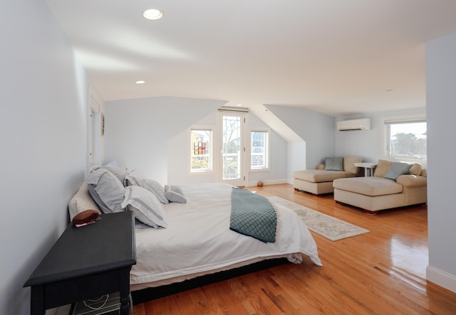 bedroom featuring light hardwood / wood-style floors, multiple windows, and a wall mounted air conditioner