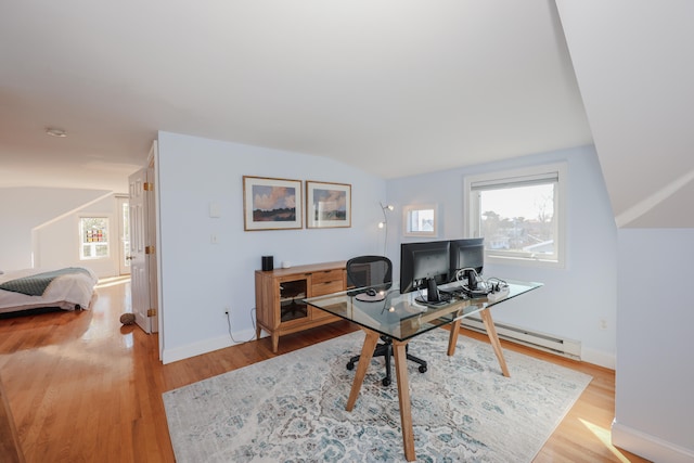 office with vaulted ceiling, a baseboard heating unit, and hardwood / wood-style flooring