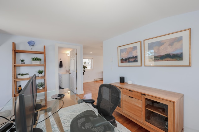 office area with light hardwood / wood-style floors and a baseboard heating unit