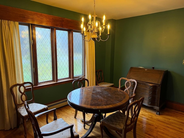 dining area with a baseboard heating unit, a notable chandelier, and light hardwood / wood-style flooring