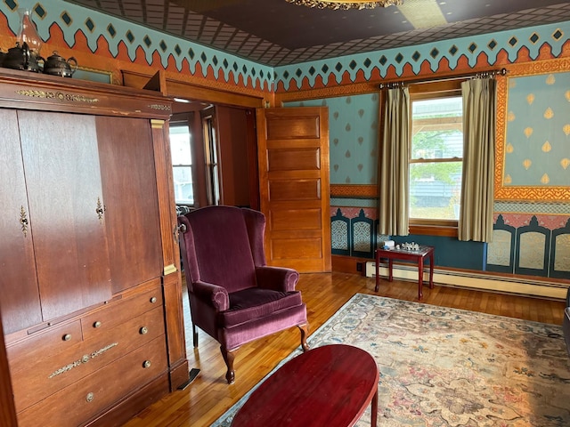 sitting room featuring wood-type flooring and a baseboard heating unit