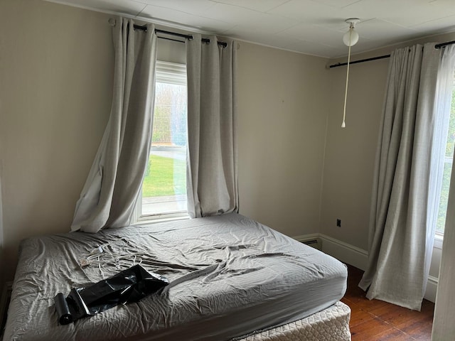 bedroom with ceiling fan, multiple windows, and dark hardwood / wood-style floors