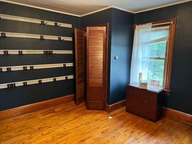 bedroom with a closet, light wood-type flooring, and crown molding