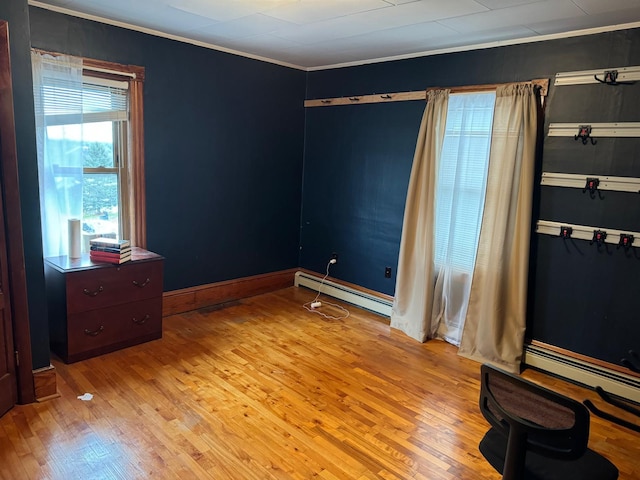 bedroom featuring baseboard heating, light wood-type flooring, and crown molding