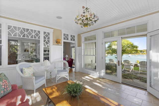 sunroom / solarium featuring a water view and an inviting chandelier