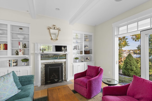 living room with built in features, beamed ceiling, and wood-type flooring