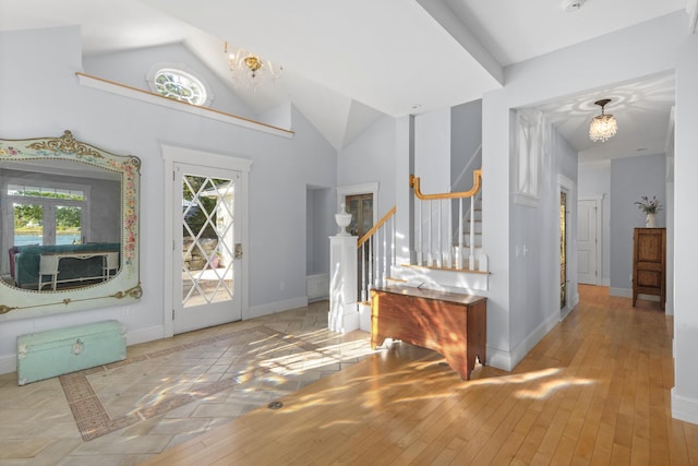 entryway with lofted ceiling, light wood-type flooring, french doors, and a chandelier