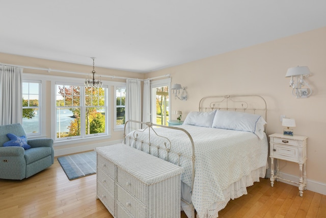 bedroom with light hardwood / wood-style flooring, multiple windows, and a notable chandelier