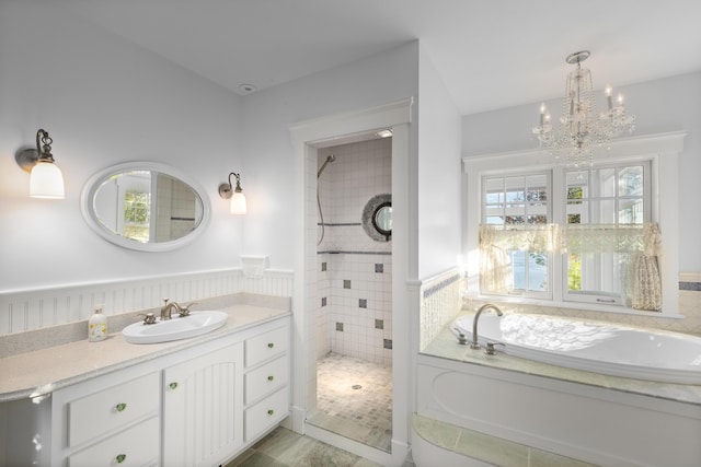 bathroom with vanity, independent shower and bath, and an inviting chandelier