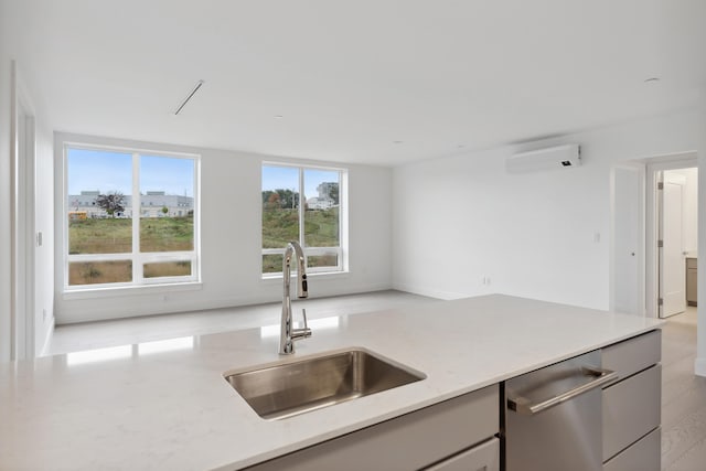 kitchen featuring dishwasher, a wall mounted AC, sink, and light wood-type flooring