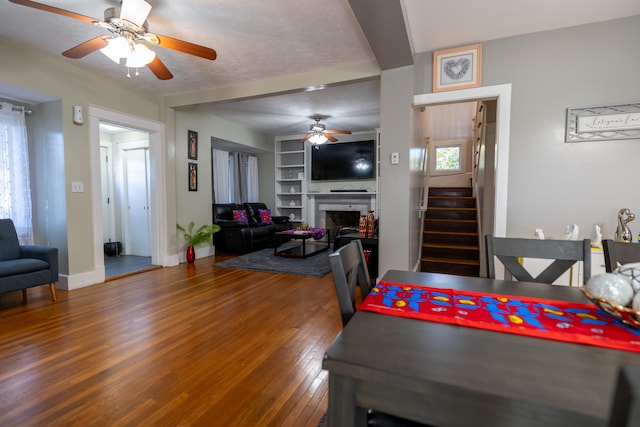 dining space featuring a textured ceiling, hardwood / wood-style flooring, built in features, and ceiling fan