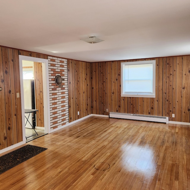 unfurnished room featuring a baseboard heating unit, hardwood / wood-style flooring, and wooden walls