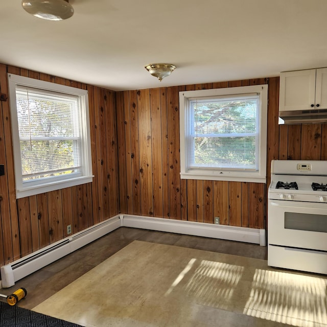 interior space featuring white cabinets, white gas range oven, a baseboard radiator, and wood walls