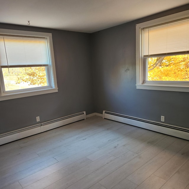 unfurnished room with baseboard heating and light hardwood / wood-style floors