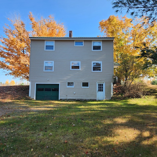 back of property with a yard and a garage