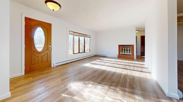 foyer featuring a baseboard radiator, light wood-type flooring, and a brick fireplace