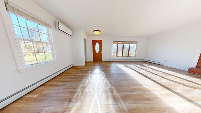 entryway with light wood-type flooring, a wall mounted AC, a baseboard radiator, and a wealth of natural light