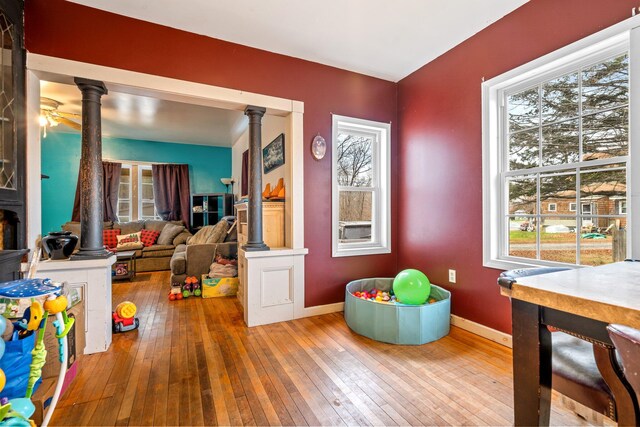 rec room with decorative columns, wood-type flooring, and ceiling fan