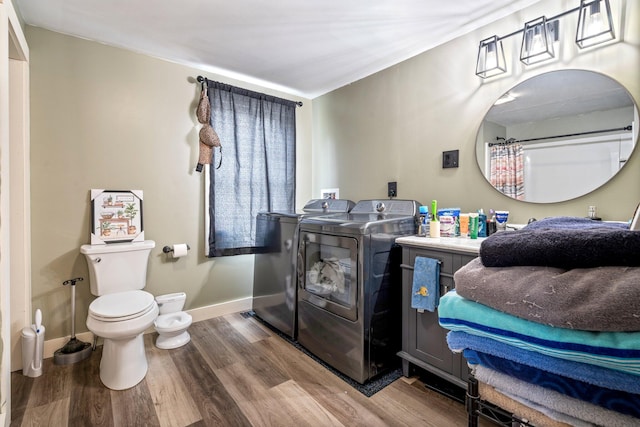 bathroom with washing machine and clothes dryer, wood-type flooring, and toilet