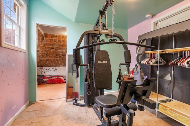 exercise room with vaulted ceiling and carpet