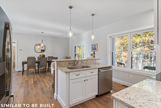 kitchen featuring stainless steel appliances, sink, pendant lighting, and white cabinets