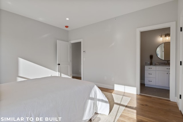 bedroom featuring wood-type flooring, connected bathroom, and sink