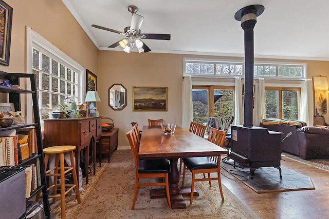 dining space featuring a wood stove, ornamental molding, and ceiling fan