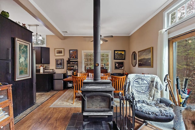 living room with light wood-type flooring, ceiling fan, a wood stove, and crown molding