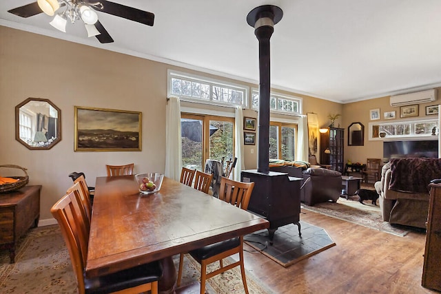 dining space featuring ceiling fan, crown molding, a wall mounted AC, and light wood-type flooring