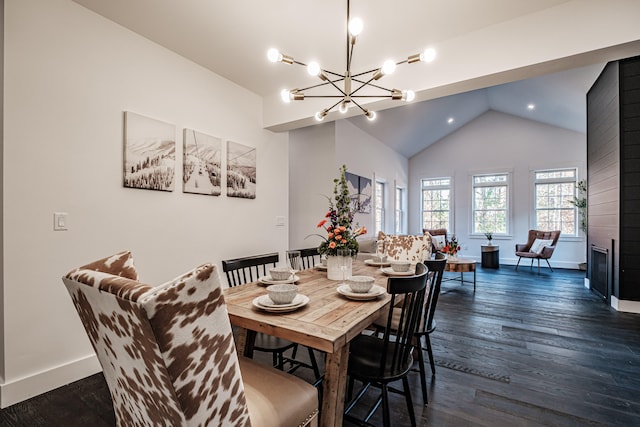 dining space with lofted ceiling, dark hardwood / wood-style floors, a chandelier, and a large fireplace