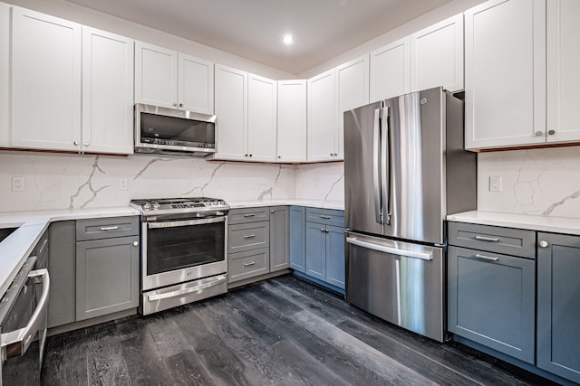 kitchen with gray cabinetry, tasteful backsplash, appliances with stainless steel finishes, and dark wood-type flooring