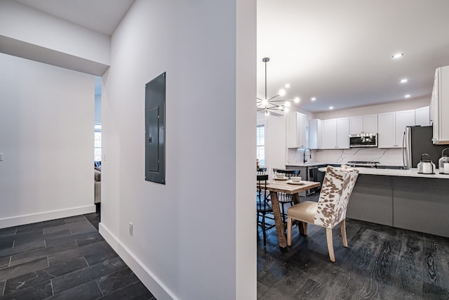 dining space featuring sink, an inviting chandelier, electric panel, and dark hardwood / wood-style floors