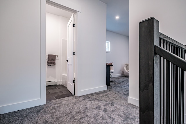 hall with a baseboard radiator and dark colored carpet