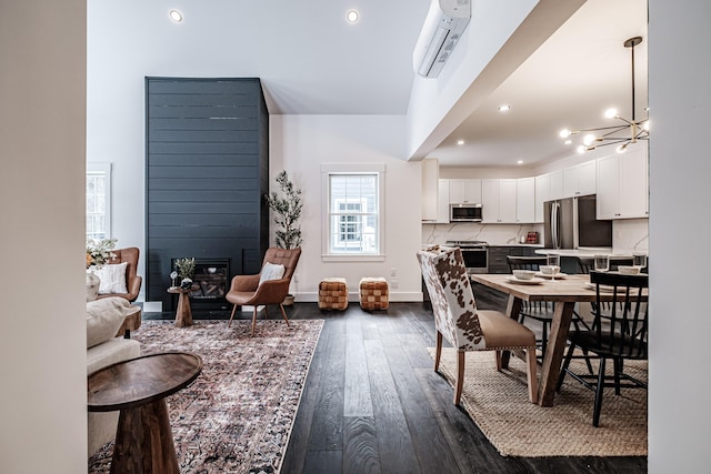 dining space featuring a notable chandelier, dark wood-type flooring, a wall mounted AC, and a large fireplace