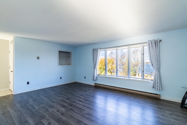 spare room featuring a baseboard radiator and dark hardwood / wood-style floors