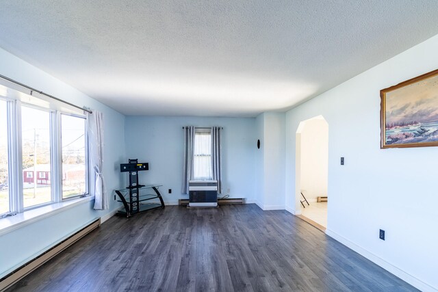 unfurnished room featuring a baseboard radiator, dark wood-type flooring, a textured ceiling, and plenty of natural light