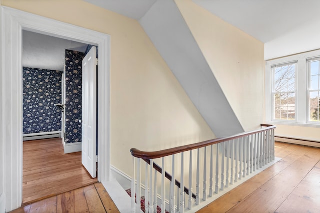 corridor with vaulted ceiling, a baseboard heating unit, and hardwood / wood-style floors