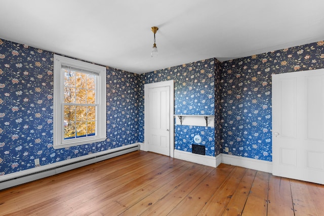 empty room featuring hardwood / wood-style flooring and a baseboard radiator