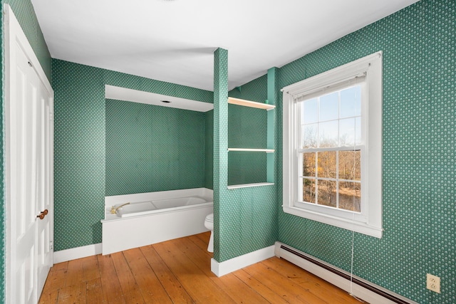 bathroom with baseboard heating, independent shower and bath, hardwood / wood-style flooring, and toilet