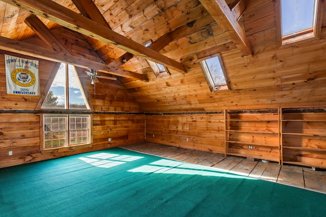 additional living space featuring lofted ceiling with skylight, hardwood / wood-style flooring, wooden walls, and ceiling fan