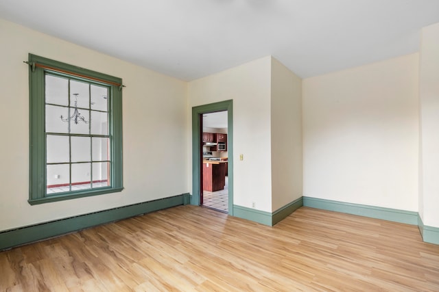 empty room featuring light hardwood / wood-style flooring and a baseboard heating unit