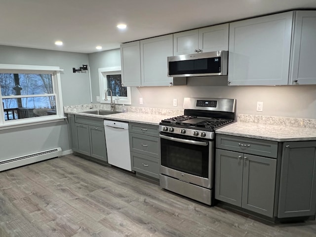 kitchen with gray cabinetry, light hardwood / wood-style flooring, appliances with stainless steel finishes, and sink