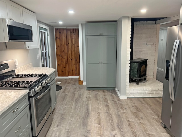 kitchen featuring light hardwood / wood-style flooring, stainless steel appliances, and a wood stove