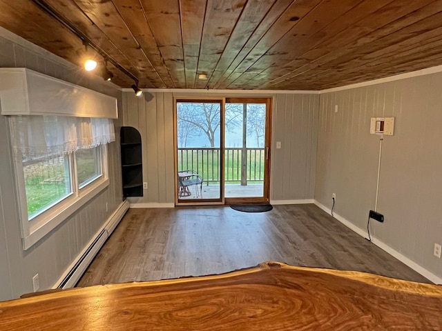 empty room featuring wooden ceiling, a baseboard heating unit, wooden walls, and hardwood / wood-style floors