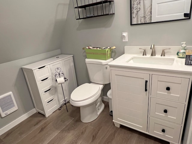 bathroom featuring vanity, toilet, hardwood / wood-style flooring, and heating unit