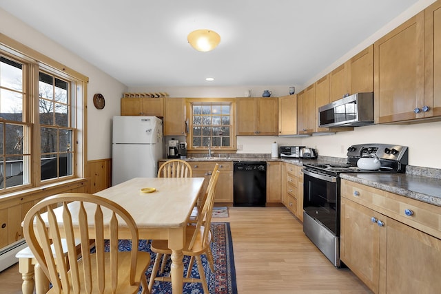 kitchen featuring wood walls, light wood-type flooring, sink, and appliances with stainless steel finishes